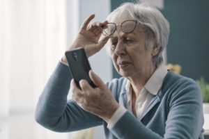 Senior woman, with vision problems, having difficulty reading messages on cellphone