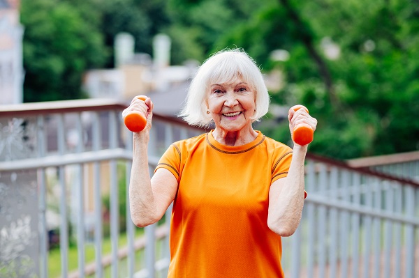 Beautiful sportive senior woman training outdoors - Mature adults old female doing fitness workout exercises in a park to stay healthy and fit