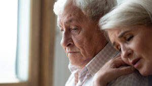 Worried middle aged woman comforting depressed elder husband, experiencing grief.